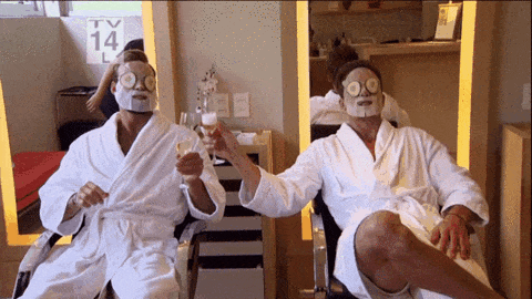 Dois homens sentados com máscaras de tratamento brindando